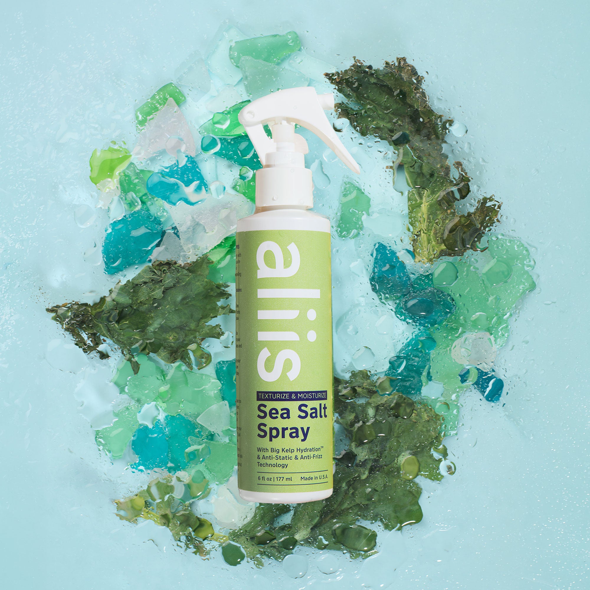 aliis Sea Salt Spray bottle on a textured blue background with green and white elements