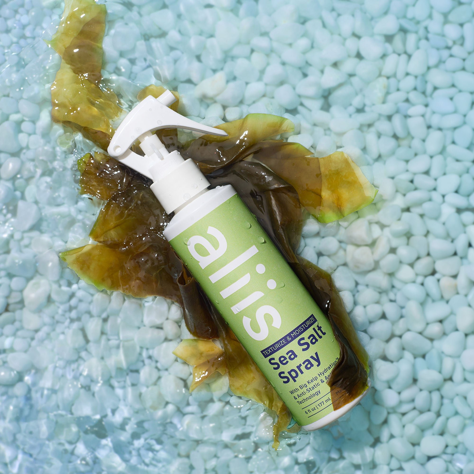 Aliis Sea Salt Spray bottle on a textured blue surface with kelp